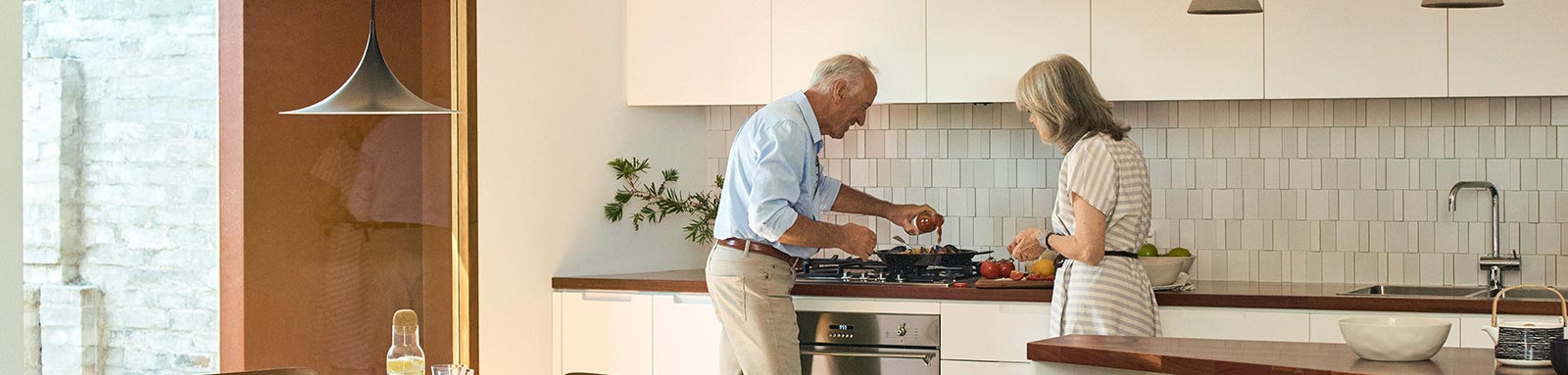 A retired couple cooking muselis in kitchen
