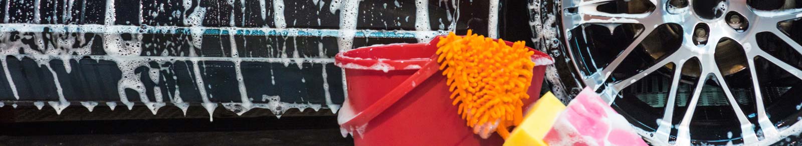 Car with soap suds and a red bucket with washing equipment