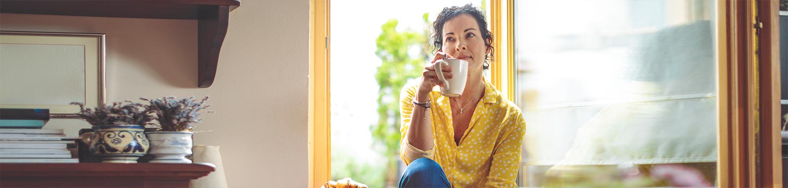 Woman thinking while drinking coffee by the window