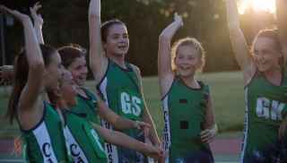 Netball girls with hands raised in the air