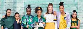 Netball girls standing next to a green wall