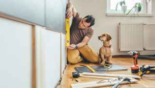 Man with a spirit level and a dog in a house