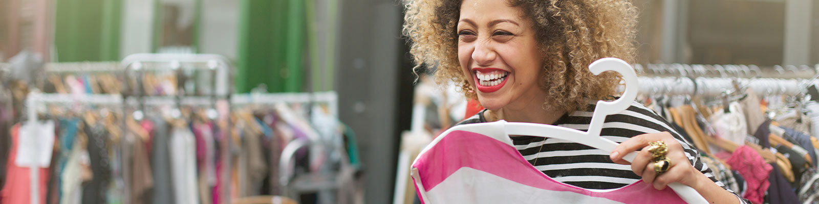Woman holding shirt laughing in clothing store