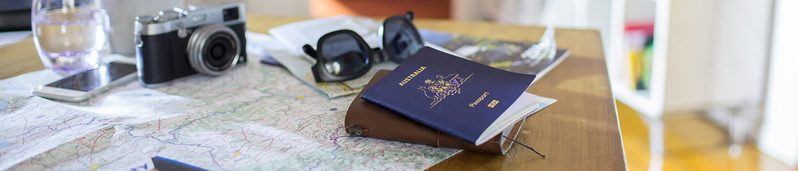 Table with camera, sunglasses and passport scattered on top