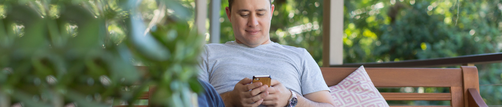 Man sitting on bench smiling at mobile phone