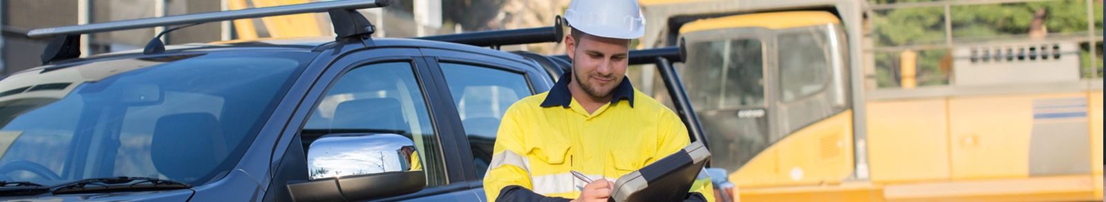 A worker man is standing with his car at the construction site