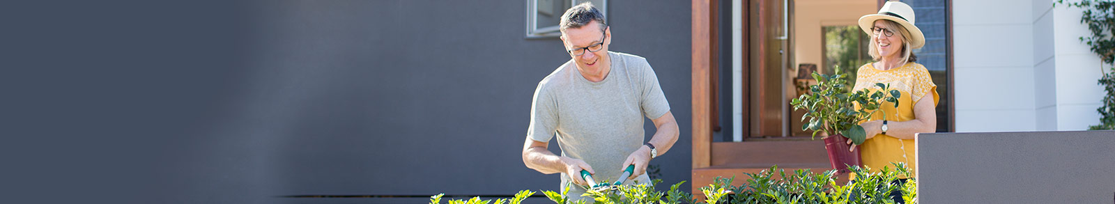 A couple is gardening outside of their house