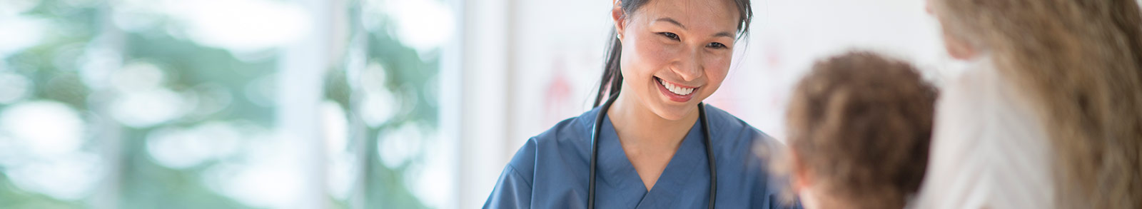 A female nusre in blue uniform smiling at little child