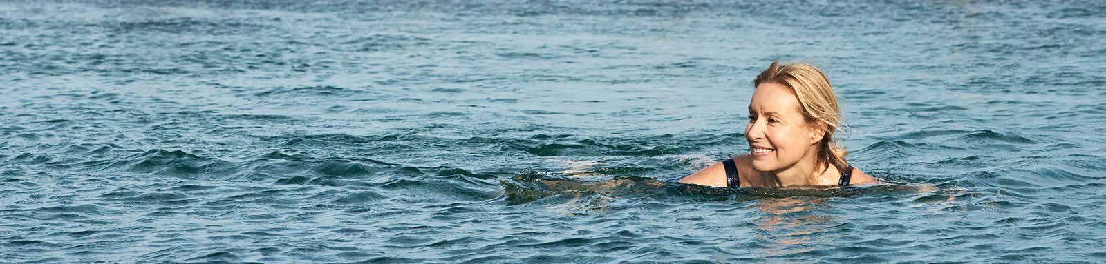 A woman is smiling in big blue ocean