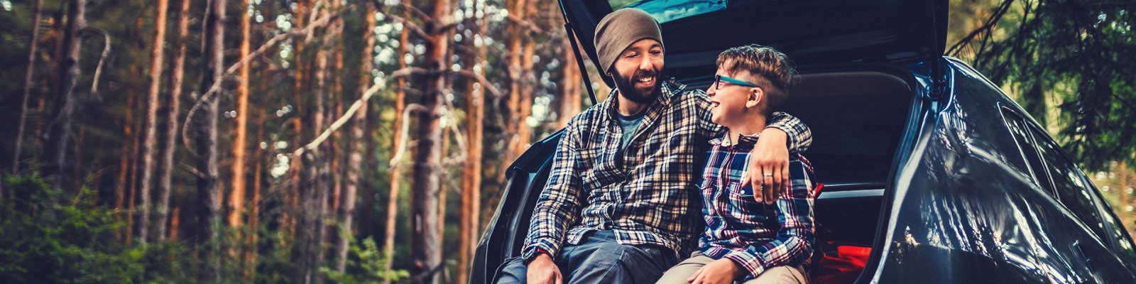 Father and son camping sitting in boot