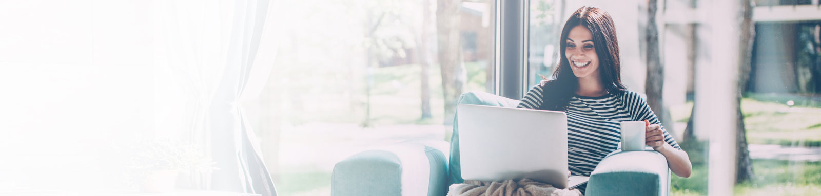 Young woman drinking tea with laptop