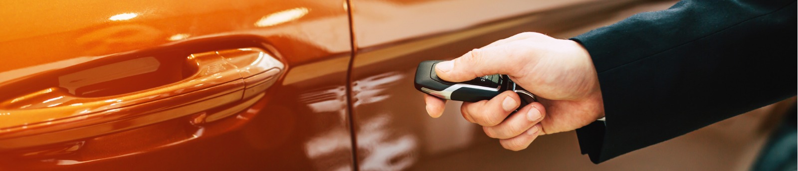 Close up of hand holding smart key up to car door