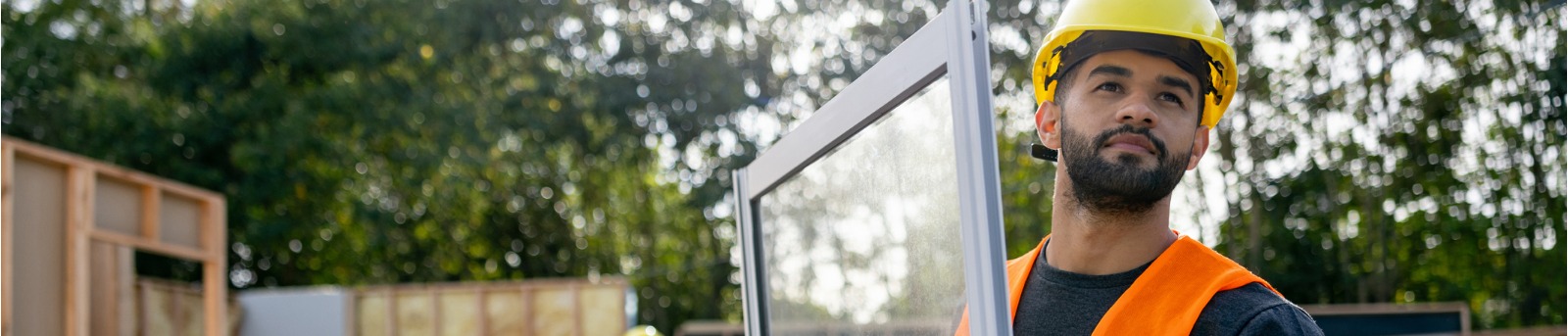 Construction worker carrying a window panel at a construction site