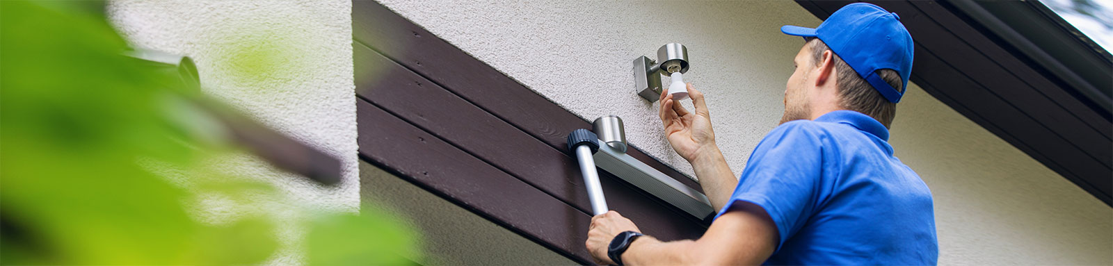 Electrician standing on ladder fixing light