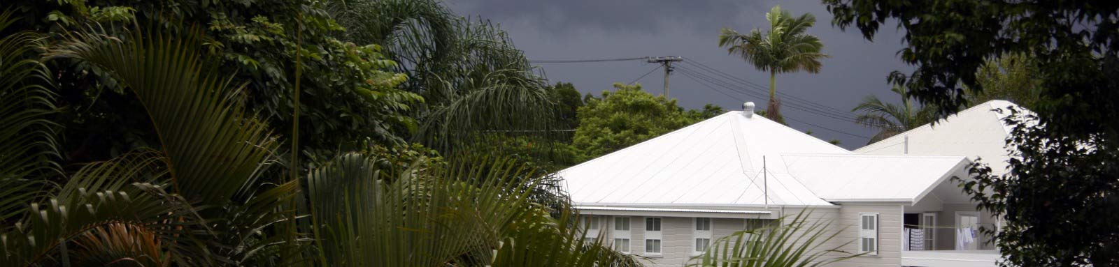 House surrounded by trees with grey clouds overhead