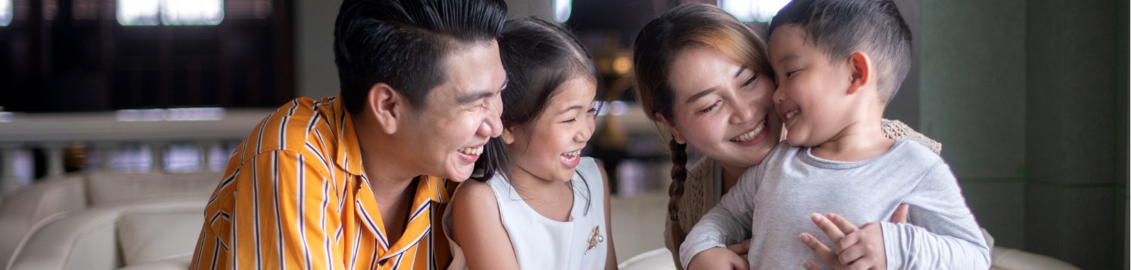 Man, woman and two children smiling on couch