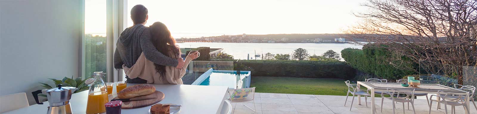 Couple in their kitchen looking out onto lake view