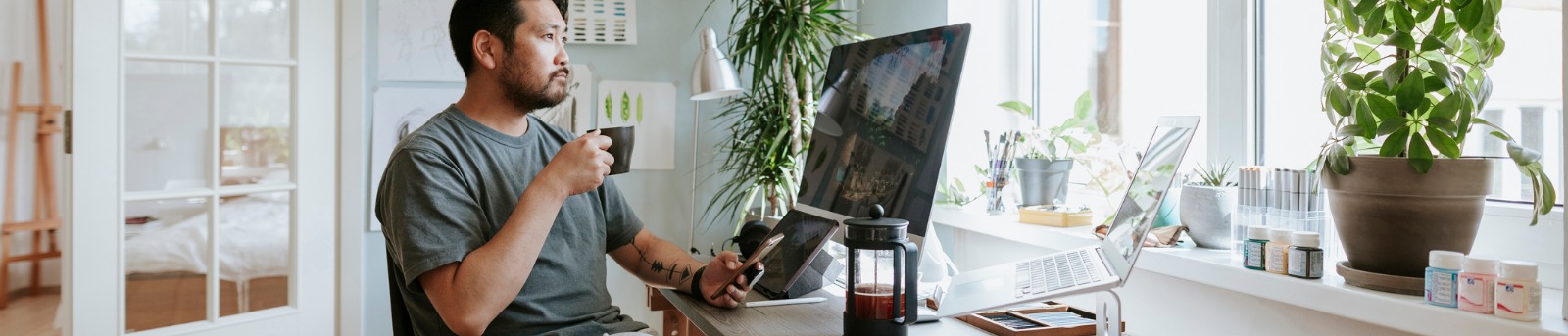 Man working in his home office while drinking coffee