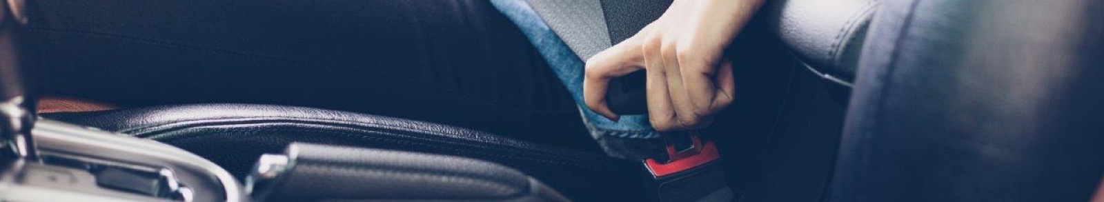 Woman putting on a seat belt in a car