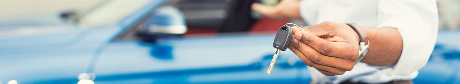 Man holding car keys to a blue car