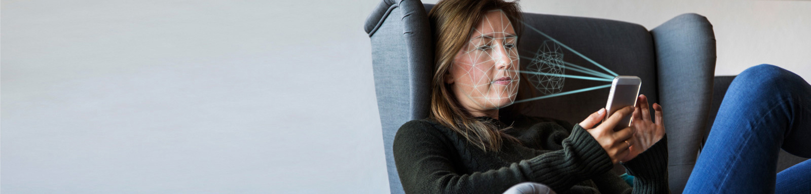 Woman sitting on chair with mobile phone using face recognition