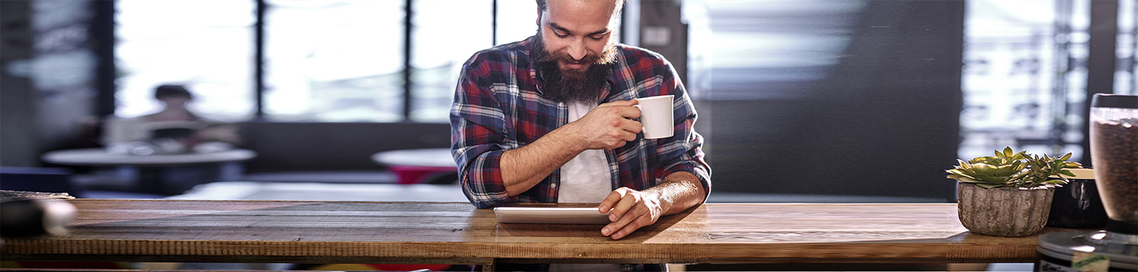 A man looking at a tablet while drinking a cup of coffee