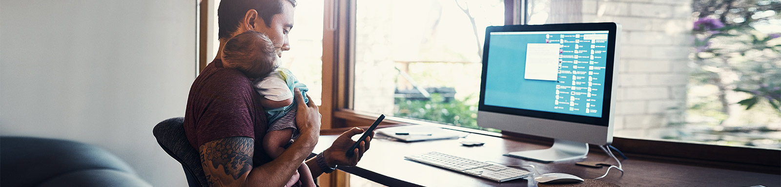 Father iwth baby in study room looking at mobile phone