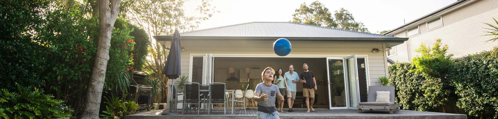 Kid playing with blue ball in backyard
