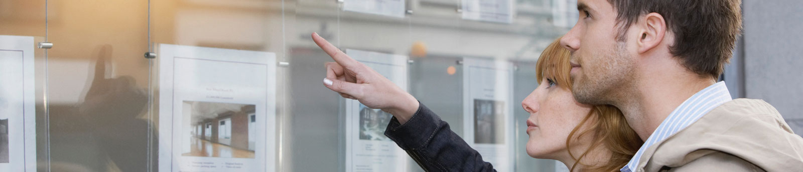 Couple looking at houses for sale on listing shop window