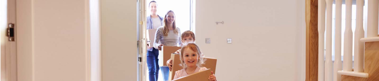 Family holding moving boxes in their home