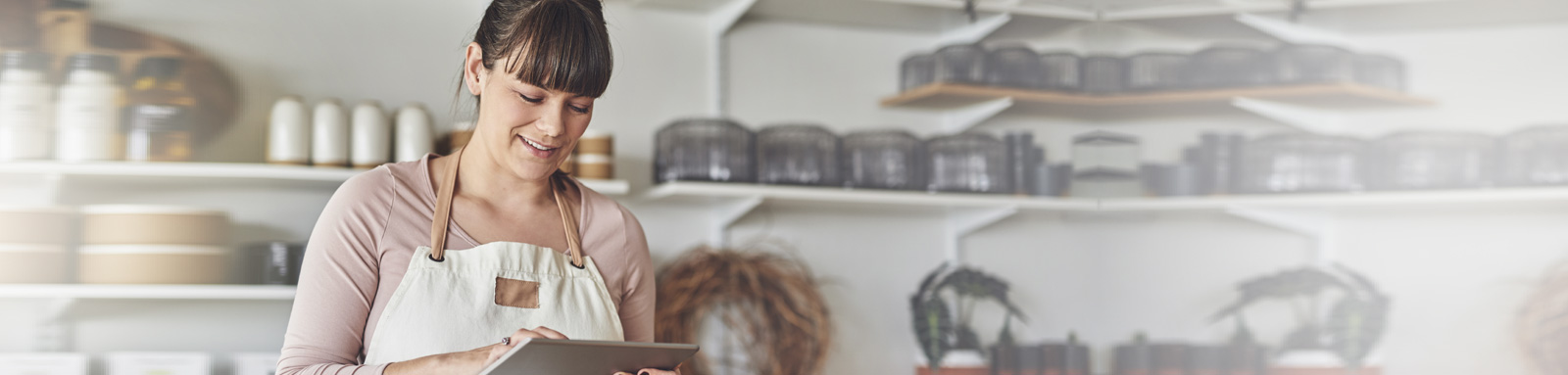 A woman wearing Apron using digital tablet in her florist shop 