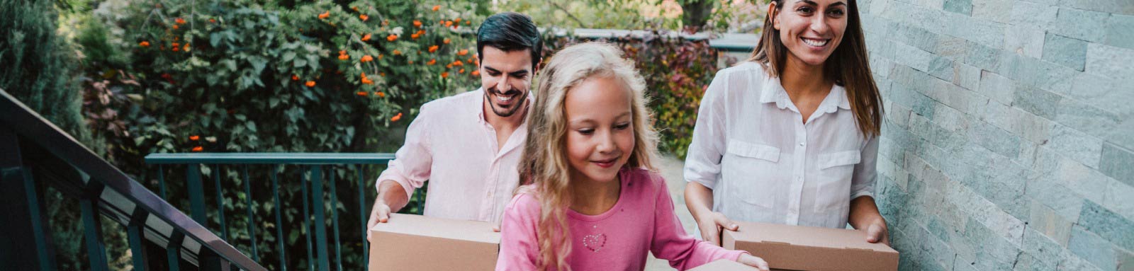 A girl woman and man carrying boxes up stairs