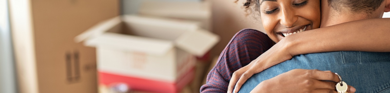 Woman holding key hugging man by moving boxes