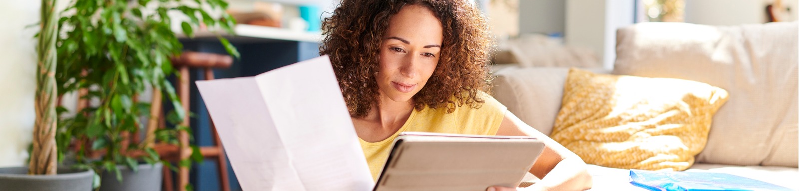 Woman looking at papers and tablet screen