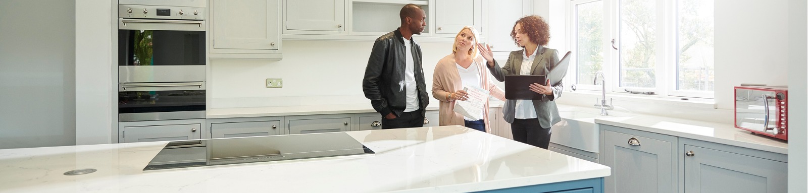 Woman with folder showing couple empty kitchen