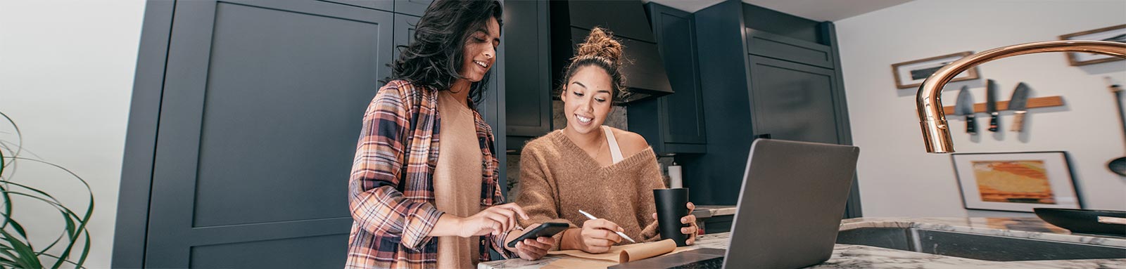 Two women at a kitchen with laptop and calulator