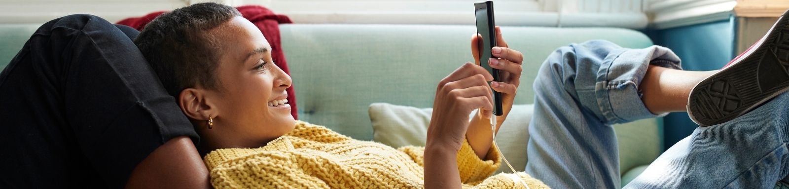 Girl in her 20s holding a mobile phone on the couch