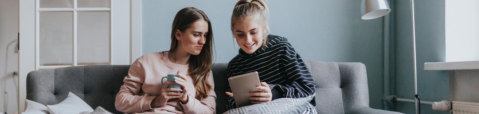 Girls sitting on a couch looking at their tablet