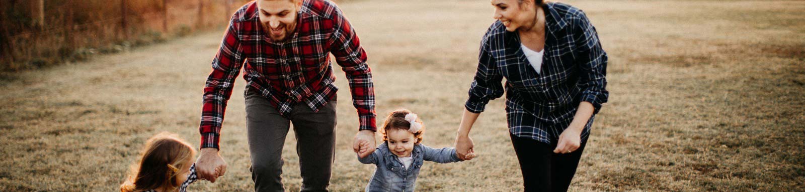 Smiling man and woman holding childrens hands paddock