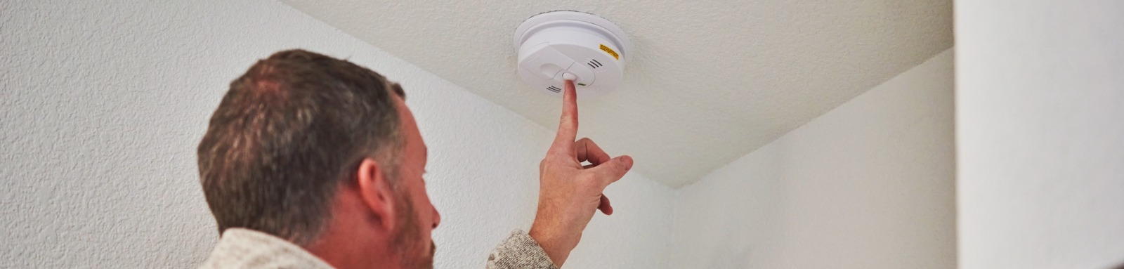 male checking the working condition of a smoke detector