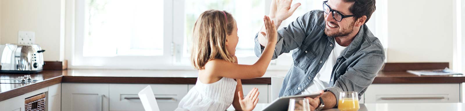 Father and daughter high fiving in the kitchen