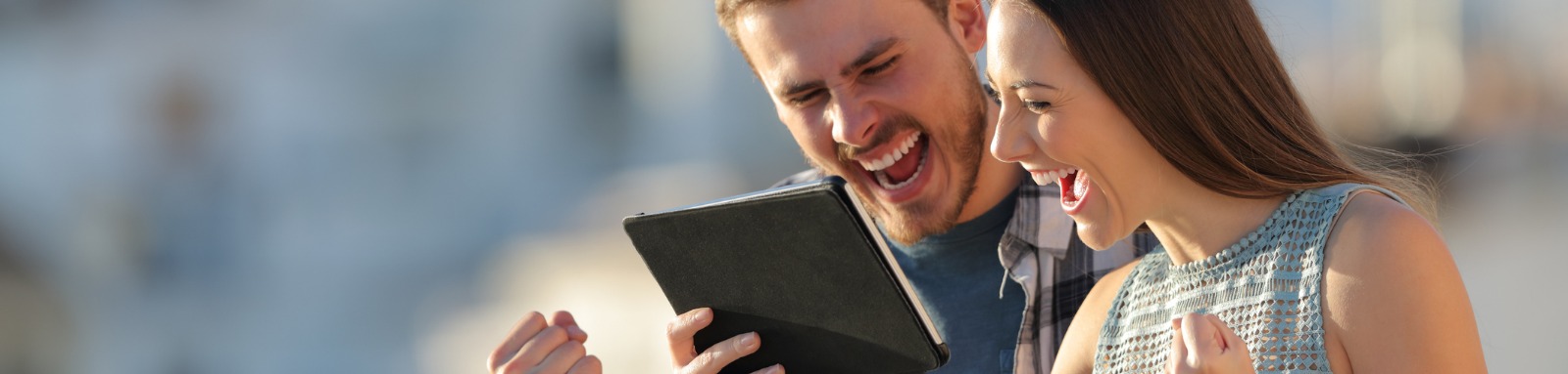 Excited woman and man grinning at ipad