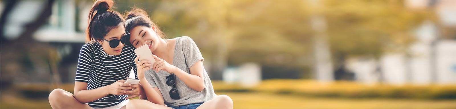 Two girls sitting and smiling with a phone