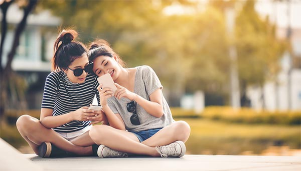 Girls sitting and smiling with phone