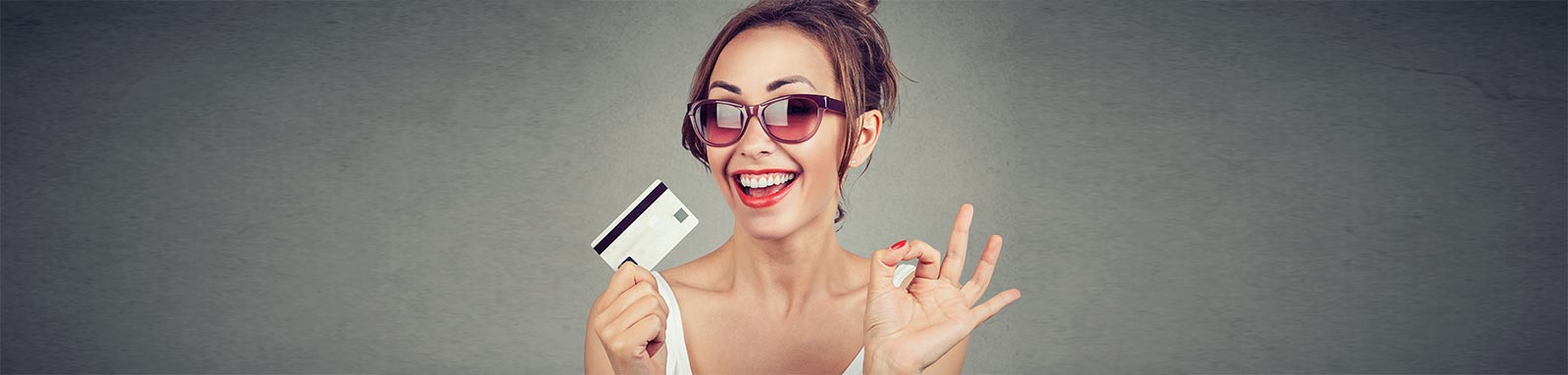 Woman wearing sunglasses with credit card smiling