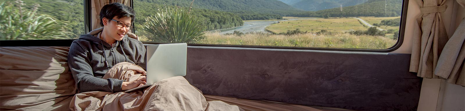 Man with laptop in bed of a campervan