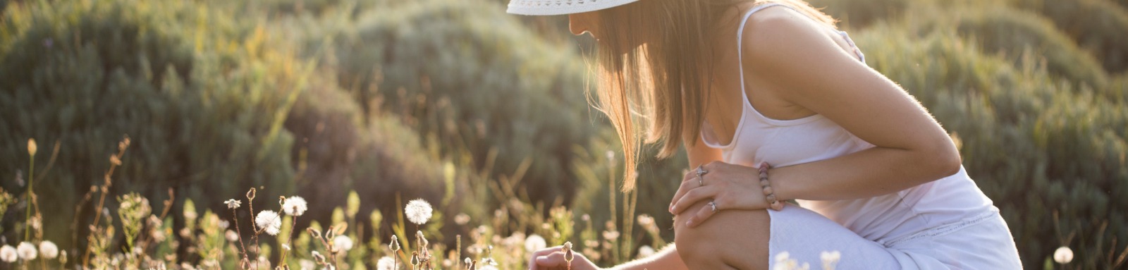 Woman wearing sunhat in a field picking flowers