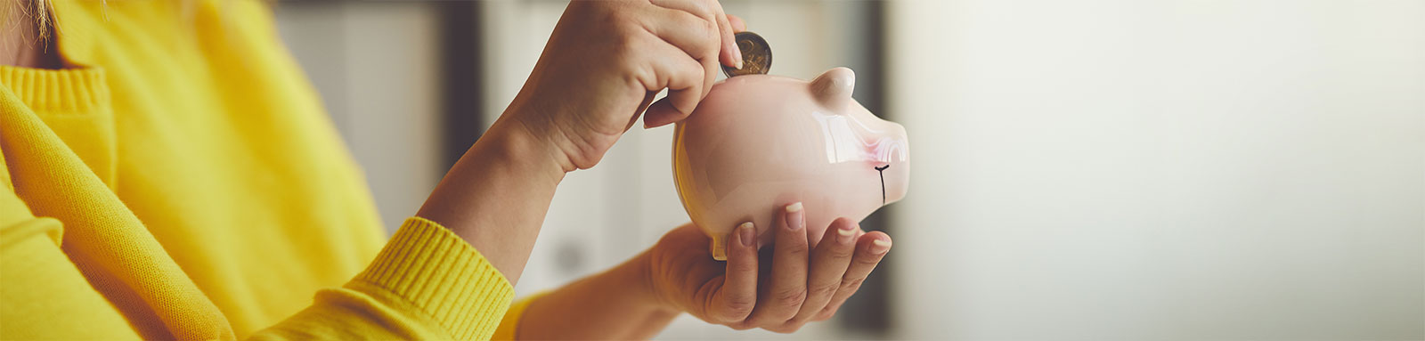 Woman putting coin in a pink piggy bank