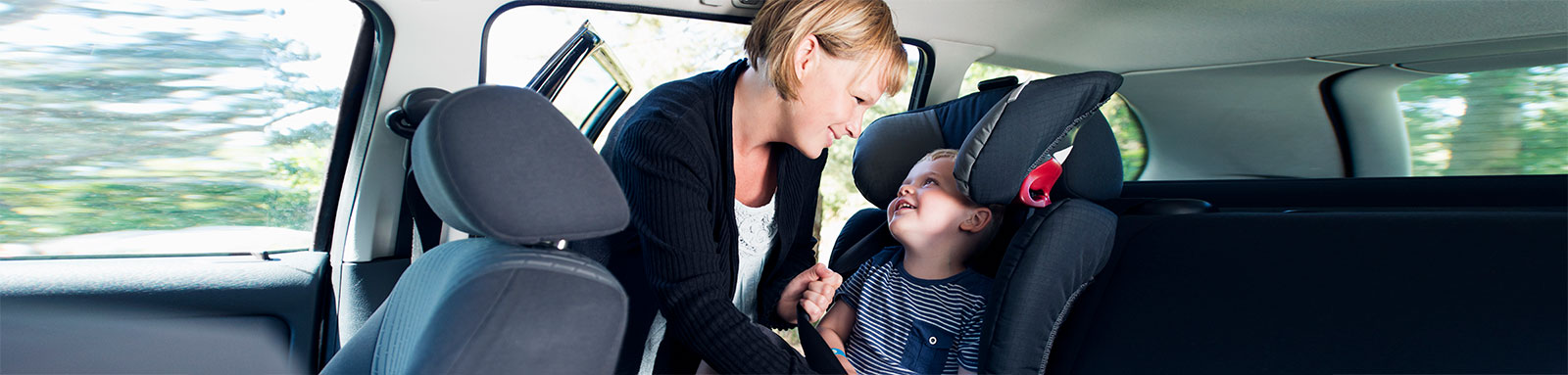 Mum putting toddler in car seat