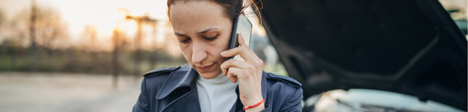 woman on phone next to damaged car